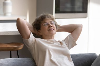 Mutlu, orta yaşlı, emekli kadın evinde dinleniyor..