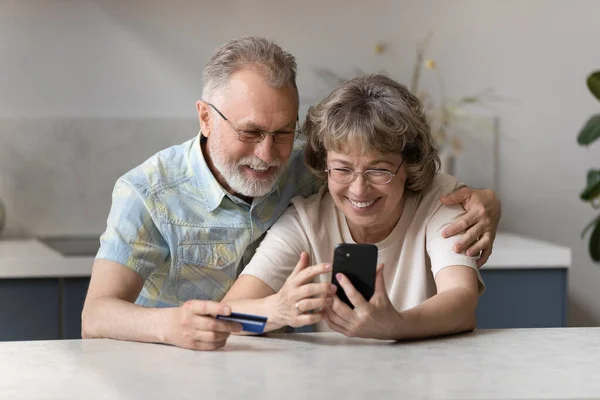 Mosolygós középkorú pár vásárol mobil app. — Stock Fotó