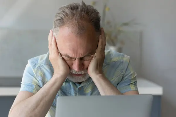 Frustrated middle aged man having problems using computer.
