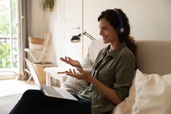 Happy remote employee wearing headphones, using laptop for conference meeting