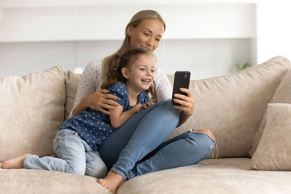 Feliz vínculo joven madre e hija pequeña usando el teléfono celular. — Foto de Stock