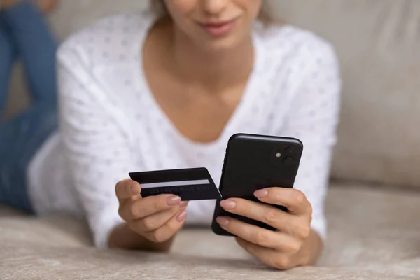 Acercamiento mujer joven sosteniendo el teléfono celular y la tarjeta en las manos. — Foto de Stock