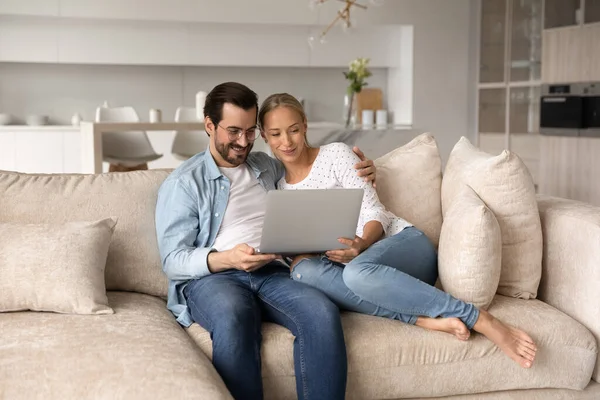 Glücklich liebendes junges Familienpaar nutzt Computer zu Hause. — Stockfoto