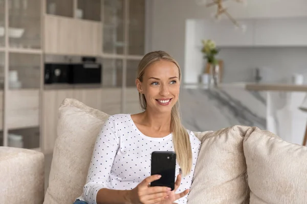 Dreamy beautiful young blonde woman using smartphone. — Stock Photo, Image