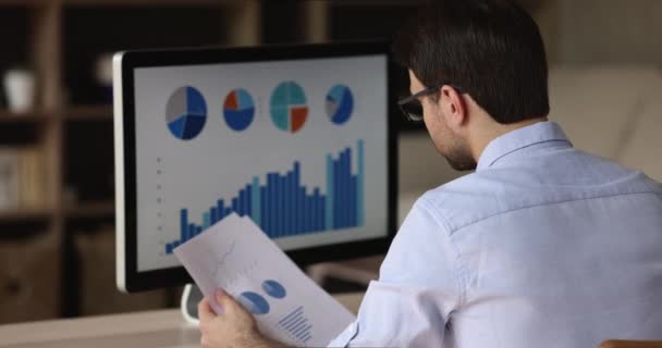 Zadní pohled mladý muž studovat grafy diagramy na obrazovce PC — Stock video