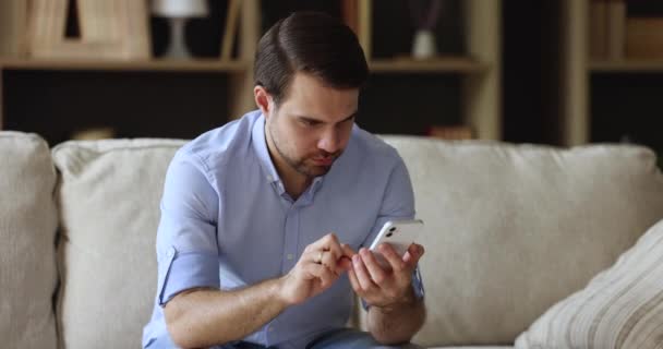 Millennial man fokuserad på telefon skärm skriva meddelande i chatten — Stockvideo