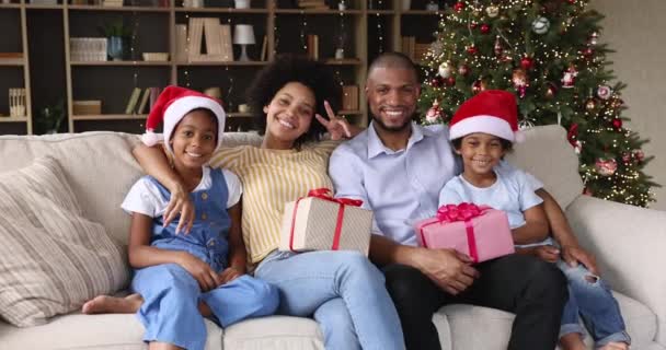 Rodzina siedzieć na kanapie z pudełkami prezentów w pobliżu choinki — Wideo stockowe