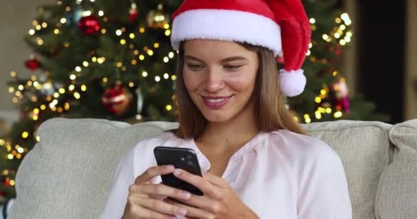 Vrouwelijke tiener kiezen Kerstmis geschenken in de webwinkel met behulp van telefoon — Stockvideo