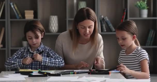 Jeune mère attentionnée enseignant le dessin aux petits enfants. — Video