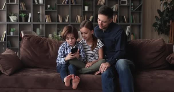 Niños pequeños usando el teléfono celular con el padre en casa. — Vídeos de Stock