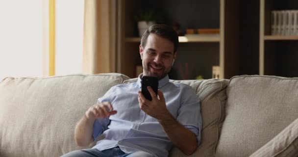 Lächelnder junger Mann trägt Kopfhörer, telefoniert per Videotelefon — Stockvideo