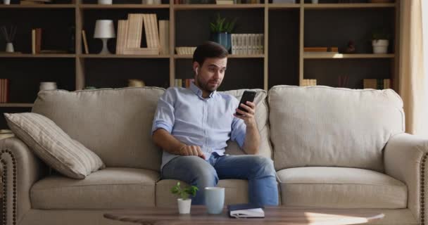 Magabiztos férfi tartsa videobeszélgetés otthonról a telefon headset — Stock videók