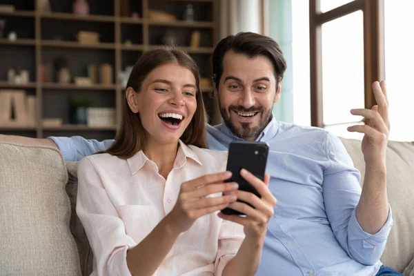 Έκπληκτο νεαρό οικογενειακό ζευγάρι κοιτάζοντας οθόνη κινητού τηλεφώνου. — Φωτογραφία Αρχείου