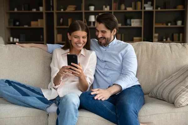 Leende vackra unga par med hjälp av mobilappar. — Stockfoto
