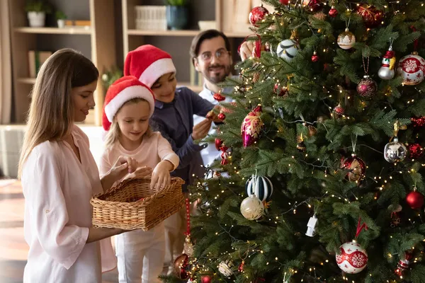 Happy loving parents decorating tree with small children. — Stock Photo, Image