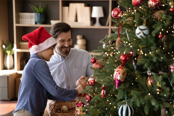 Feliz familia masculina decorando el árbol de Navidad en casa. — Foto de Stock