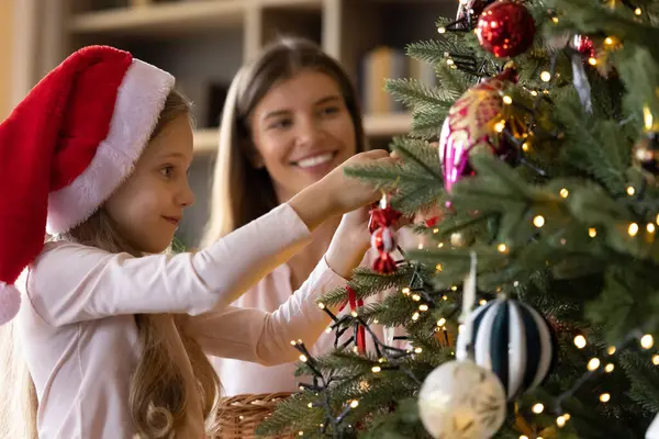Glückliches kleines Mädchen schmückt Weihnachtsbaum mit Mutter. — Stockfoto