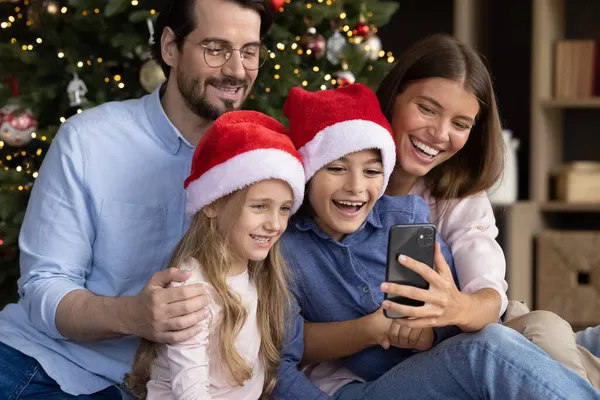 Familia afectuosa feliz usando el teléfono inteligente en casa. — Foto de Stock