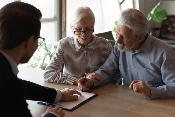 Mutlu karı-koca emekliler sigorta bürosunda kağıt imzalıyorlar.