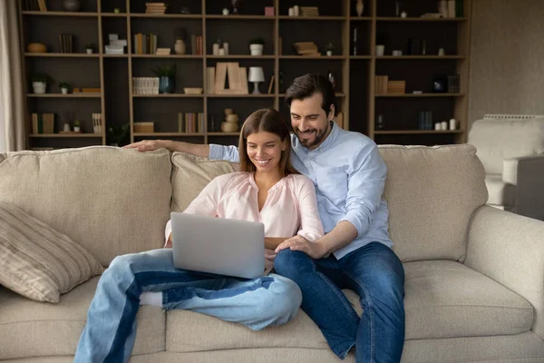 Glückliches junges Familienpaar nutzt Computer zu Hause. — Stockfoto