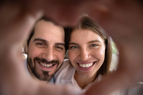 Nahaufnahme lächelndes aufrichtiges junges Familienpaar, das Herz zum Symbol macht. — Stockfoto