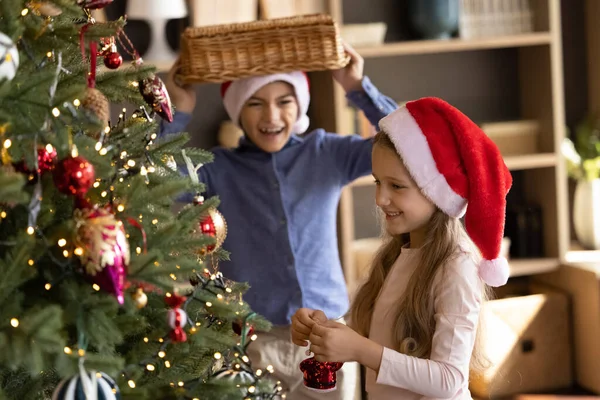Crianças pequenas alegres que decoram a árvore de Natal em casa. — Fotografia de Stock