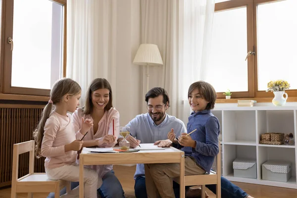 Happy parents drawing pictures with little children. — Stock Photo, Image