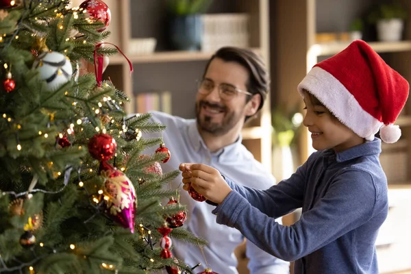 Joyful cute small kid boy decorating Christmas tree with father. — Stock Photo, Image