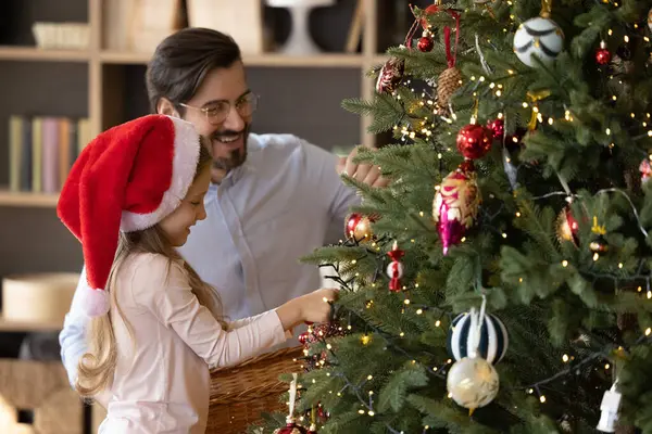 Glad liten söt liten flicka dekorera julgran med far. — Stockfoto