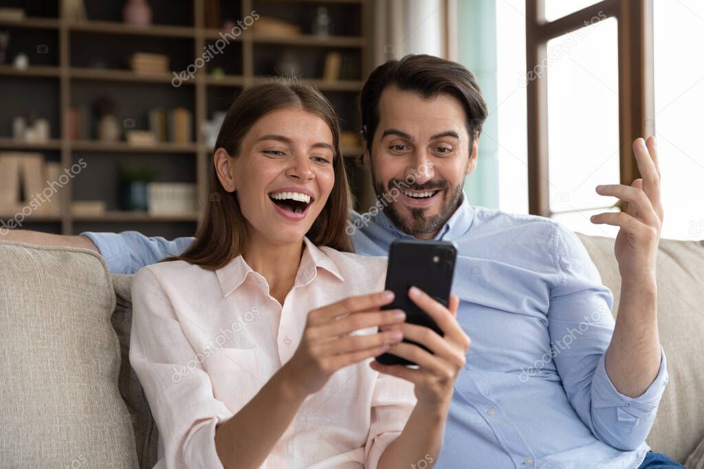 Surprised young family couple looking at cellphone screen.