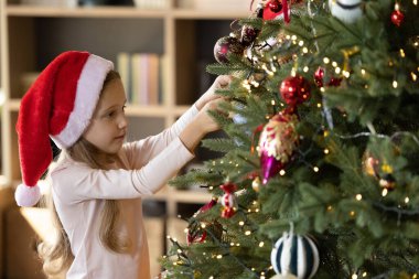 Noel ağacı süsleyen neşeli küçük kız..