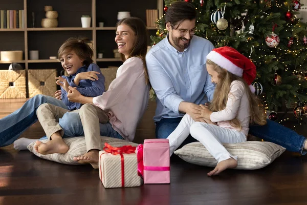 Padres felices divirtiéndose con niños cerca del árbol de Navidad. — Foto de Stock