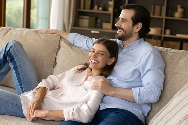 Feliz pareja milenaria soñando despierto, descansando en el sofá. —  Fotos de Stock