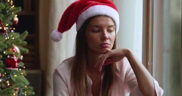 Rozrušená mladá žena ztracená v pesimistických myšlenkách pod vánočním stromem — Stock video