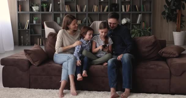 Familia feliz de dos generaciones usando el teléfono celular juntos en casa. — Vídeos de Stock