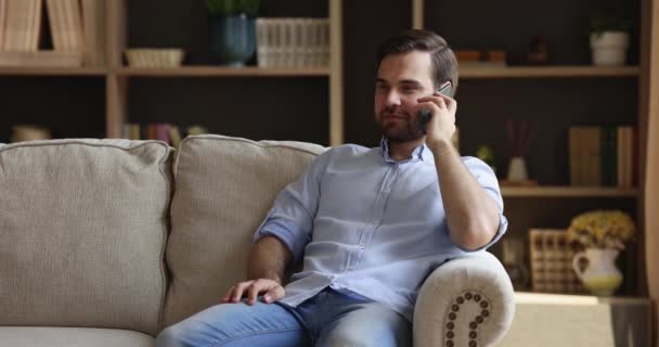 Glimlachende duizendjarige man spreken op mobiele telefoon houden informeel gesprek — Stockvideo