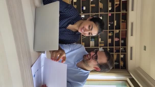 Freundliche Kollegen sitzen am Laptop am Arbeitsplatz und diskutieren über die Arbeit — Stockvideo