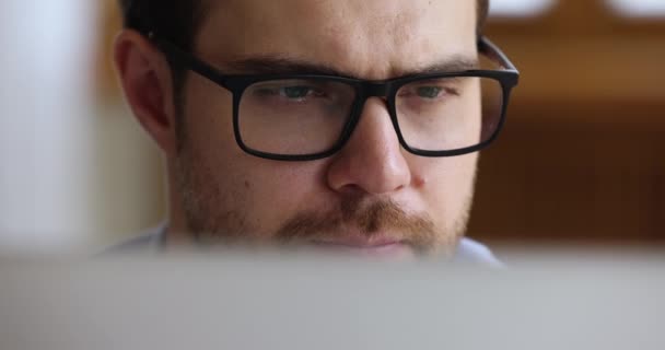 Close-up ernstige jonge zakenman werk door computer kijken op het scherm — Stockvideo