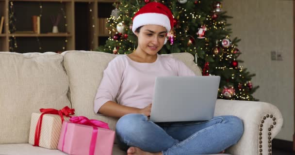 在闪闪发亮的圣诞树旁用电脑笑千年印第安女士 — 图库视频影像