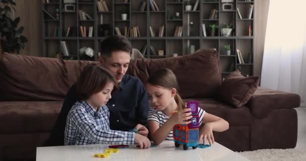 Счастливый молодой отец играет в игрушки с маленькими детьми. — стоковое видео