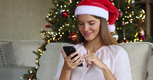 Giovane signora a Santa cap scorrere i social media al telefono — Video Stock