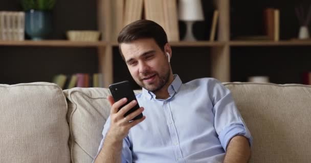 휴대용 헤드폰 채팅을 하는 긍정적 인 젊은 남자 비디오 전화 로 — 비디오