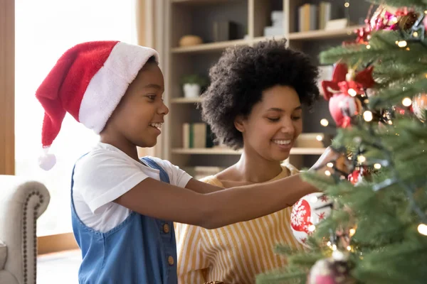 Happy african american mother decorating Christmas tree with daughter. — Stock Photo, Image