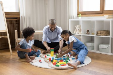 Gülümseyen Afrikalı Amerikalı baba çocuklarla oyuncak oynuyor..