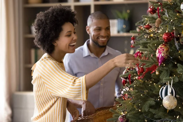 Feliz pareja de la familia de raza mixta decorando árbol de Navidad. — Foto de Stock