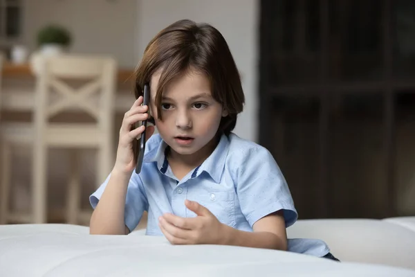 Serious gen Z kid making telephone call, talking on phone