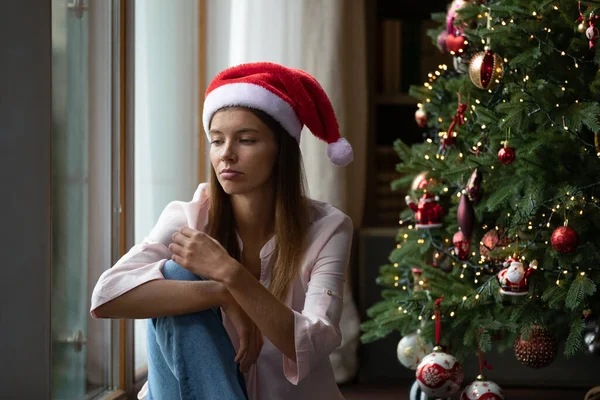 Frustrated Xmas young woman getting bored at Christmas tree — Stock Photo, Image