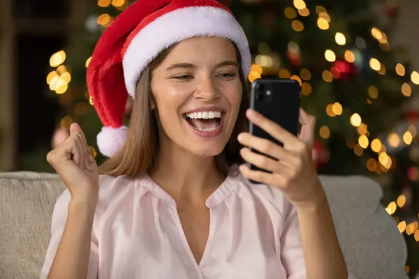 Donna eccitata in Natale Santa cap testo di lettura su smartphone — Foto Stock