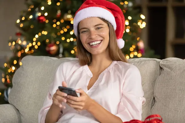 Szczęśliwy Boże Narodzenie dziewczyna w czerwony Santa kapelusz czat na telefon — Zdjęcie stockowe