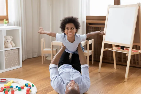 Happy young african american father lifting in air small son. — Stock Photo, Image
